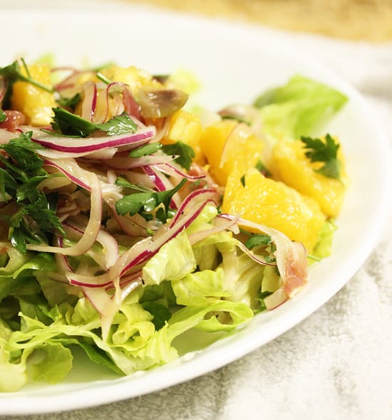 A white plate topped with salad and fruit.
