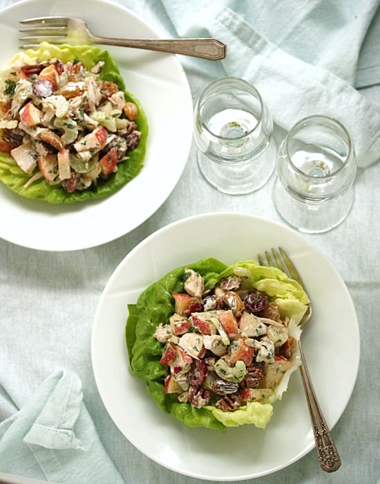 Two plates of food on a table with glasses.