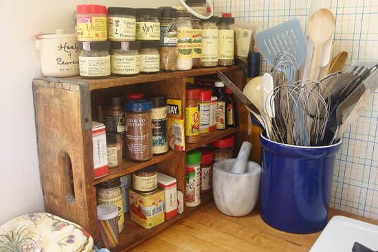 A wooden crate filled with spices and cooking utensils.
