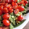 A plate of pasta and tomatoes on top of the table.