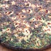 A pizza with spinach and cheese on it.
