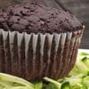 A chocolate muffin sitting on top of some green vegetables.