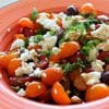 A bowl of salad with feta cheese and tomatoes.