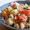 A blue bowl of food with tomatoes and potatoes.
