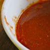 A bowl of chili sauce on top of a table.