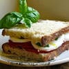 A sandwich cut in half with basil on top.