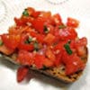 A piece of bread topped with tomato sauce and herbs.