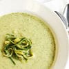A bowl of soup with some green stuff in it