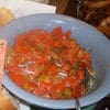 A bowl of food with tomatoes and other vegetables.