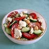 A bowl of salad with tomatoes, cucumbers and feta cheese.