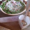 A bowl of salad next to a box of rice.