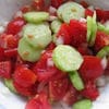 A bowl of salad with tomatoes and cucumbers.