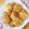 A white plate topped with biscuits covered in cheese.