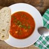 A bowl of soup with bread on the side.