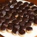 A plate of chocolate covered cookies on top of a table.